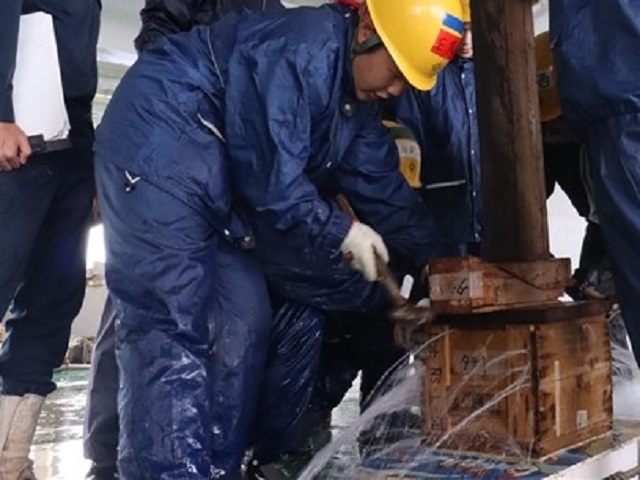 破口の処置を行う実習生 ※作業に伴い海水がかかることからマスクを外しています。